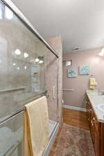 Full bath with double vanity, a stall shower, light wood-style flooring, and a textured ceiling