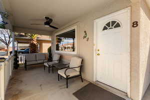 View of exterior entry featuring ceiling fan, stucco siding, and outdoor seating