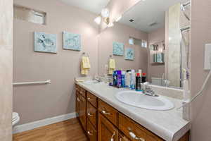 Bathroom featuring double vanity, a shower with shower door, and light wood-type flooring