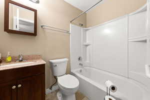 Bathroom featuring a textured wall, bathing tub / shower combination, and vanity