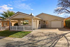 Ranch-style house with concrete driveway, a front lawn, an attached garage, a ceiling fan, and stucco siding