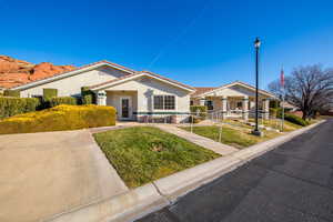View of front of home with stucco siding, a front yard, and a tile roof