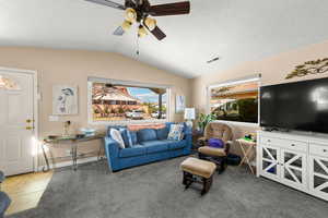 Living area with vaulted ceiling, a ceiling fan, and light carpet