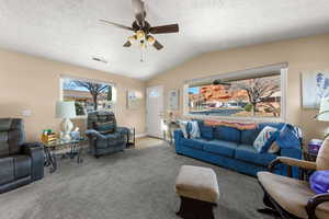 Carpeted living area with ceiling fan and a textured ceiling