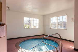 View of swimming pool featuring a sunroom and a hot tub