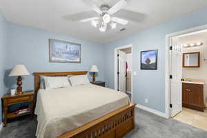 Bedroom with light colored carpet, ceiling fan, a textured ceiling, and light tile patterned flooring