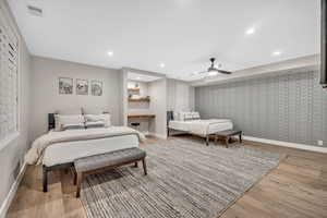 Bedroom with light wood-style floors, recessed lighting, a ceiling fan, wallpapered walls, and an accent wall