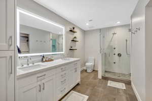 Full bath with double vanity, a stall shower, light tile patterned floors, and recessed lighting