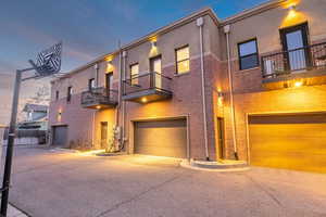 View of front of home with a balcony, an attached garage, and stucco siding