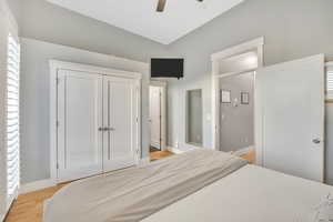 Bedroom featuring light wood-style flooring, lofted ceiling, a ceiling fan, and a closet
