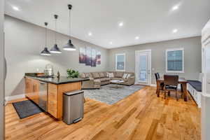 Kitchen featuring dark stone counters, pendant lighting, open floor plan, light wood-style flooring, and a peninsula