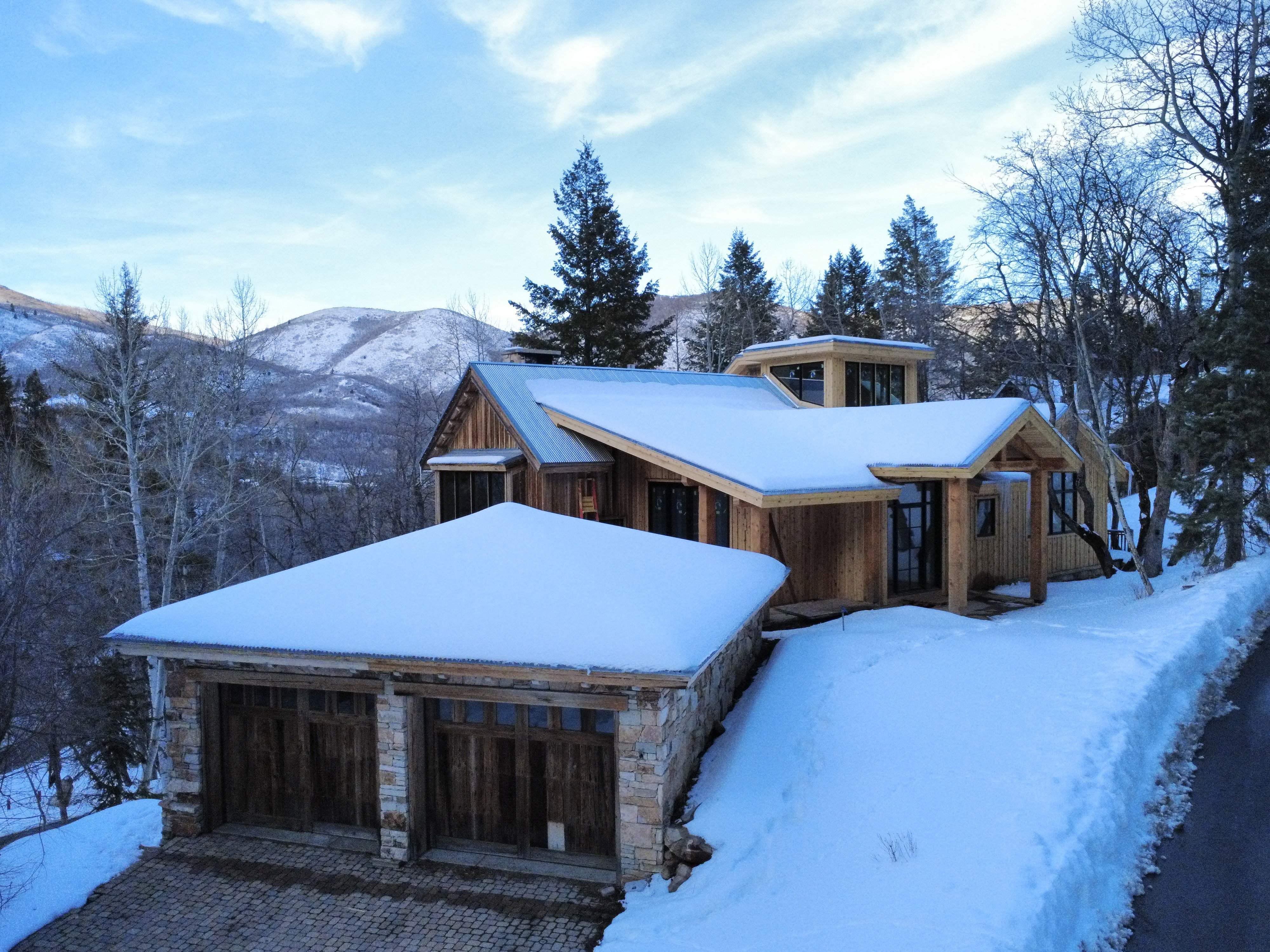 View of front facade featuring a mountain view, stone siding, a garage, and driveway