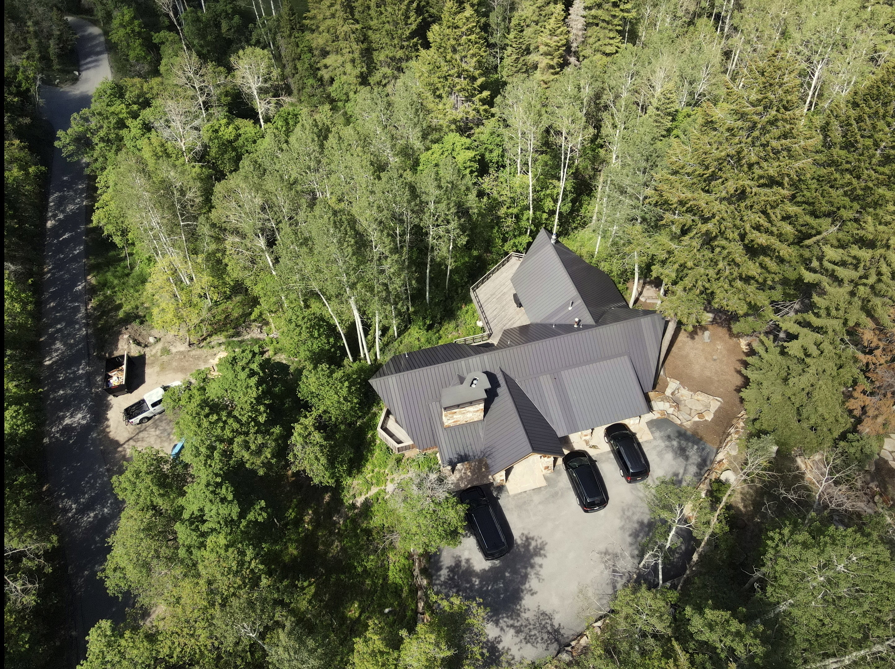 Contemporary residence featuring a dark metal roof, stone accents, and an expansive paved driveway