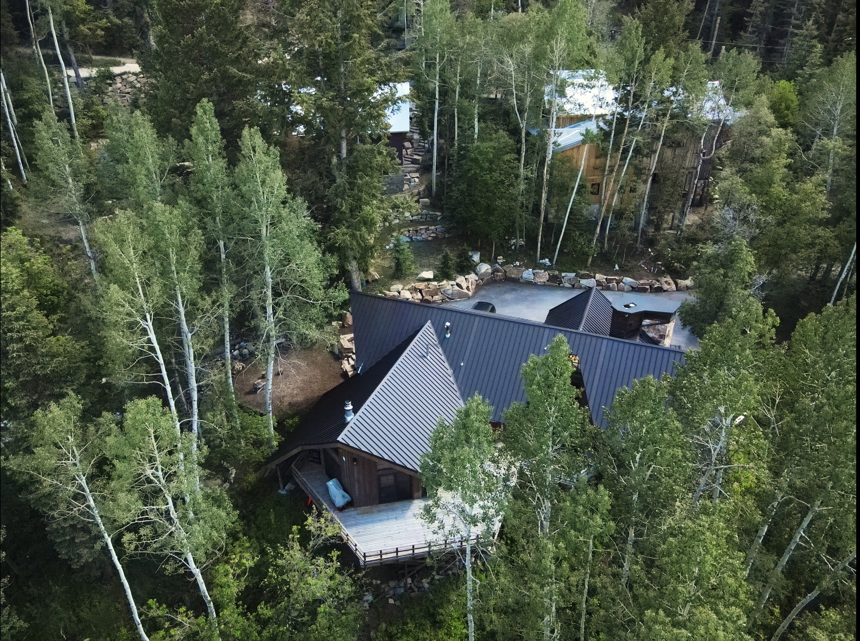 Wood-sided residence featuring a dark metal roof and an expansive exterior deck
