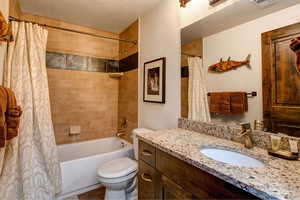 Bathroom featuring shower / bathtub combination with curtain, vanity, and a textured ceiling