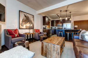 Living area with beamed ceiling, light wood finished floors, and rail lighting