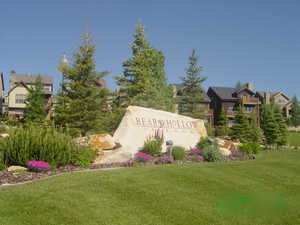 Community sign featuring a lawn and a residential view