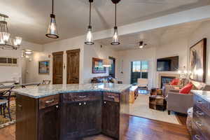 Kitchen featuring dark wood finish cabinetry, open floor plan, dark wood-type flooring, and a tile fireplace