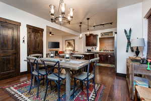 Dining area featuring ceiling fan, suspended lighting, and dark wood-type flooring