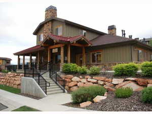 View of front facade featuring a chimney, stone siding, covered porch, and board and batten siding