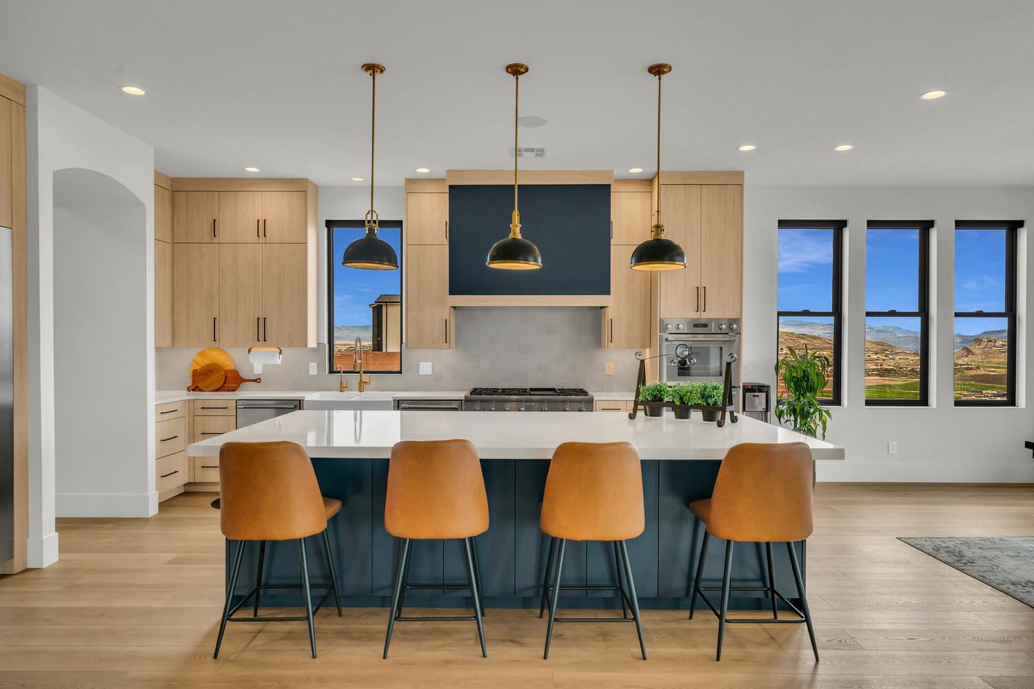 Kitchen with a large island, light wood-style floors, pendant lighting, stainless steel appliances, and two tone cabinetry