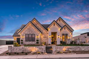 View of front of property featuring stone siding, stucco siding, driveway, and a tiled roof