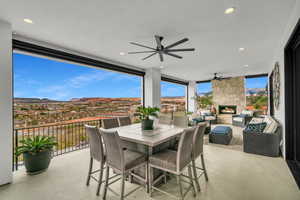 View of patio featuring a mountain view, ceiling fan, an outdoor living / dining area, and an outdoor stone fireplace