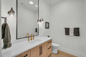 Half bath featuring light wood-type flooring, vanity, and recessed lighting