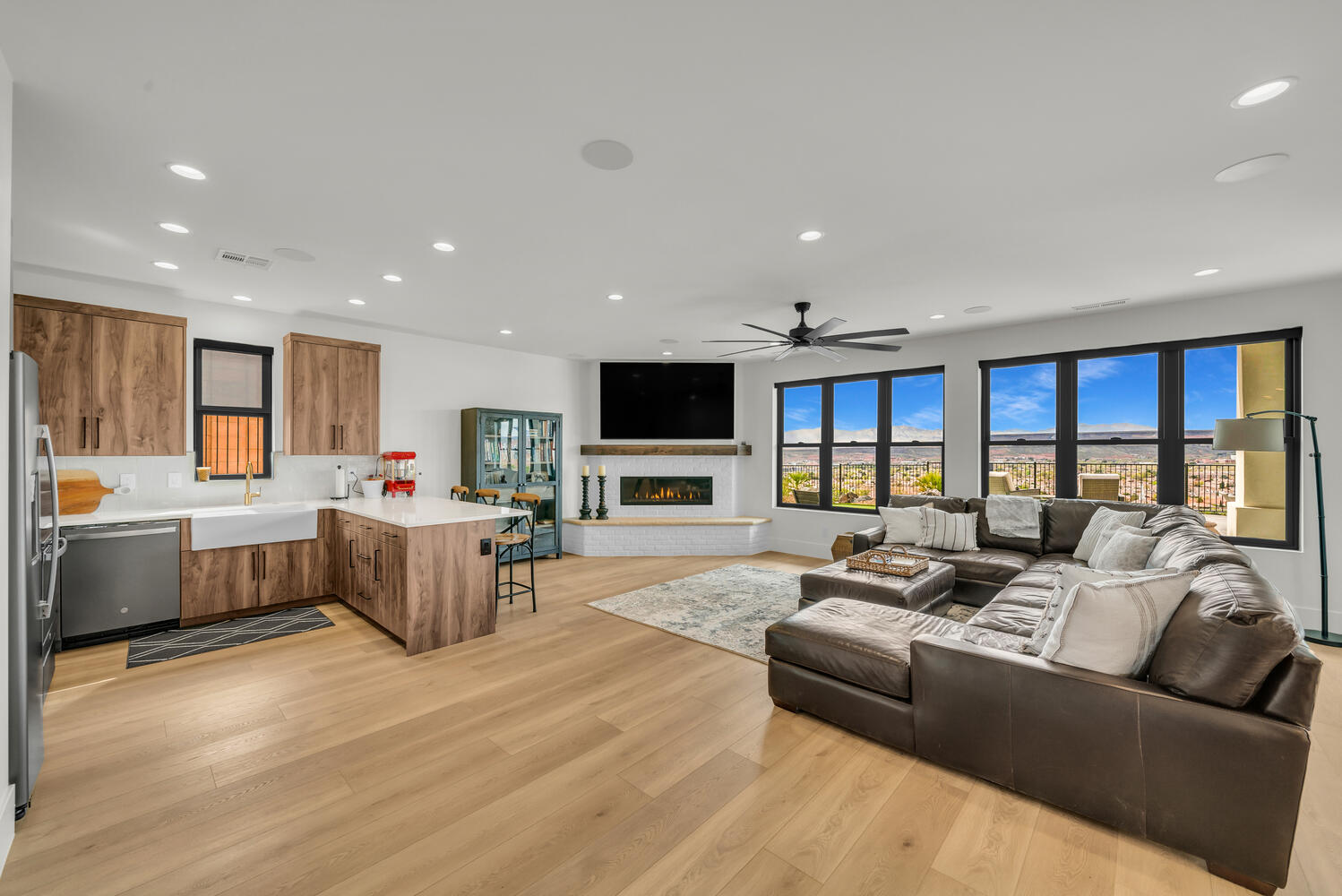 Living room with a brick fireplace, light wood-type flooring, recessed lighting, and ceiling fan