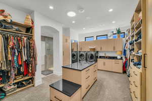 Walk in closet featuring light colored carpet and independent washer and dryer