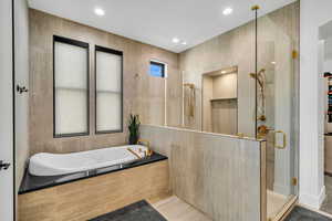 Bathroom with a shower stall, a garden tub, tile walls, recessed lighting, and a walk in closet