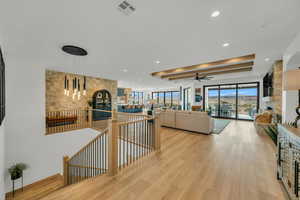 Corridor featuring an upstairs landing, a tray ceiling, light wood-style flooring, and recessed lighting