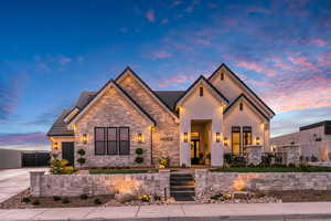 View of front of house with stone siding, stucco siding, driveway, and a tiled roof