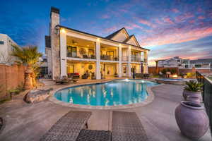 Back of house at dusk with a ceiling fan, a balcony, a patio area, a fenced backyard, and a chimney