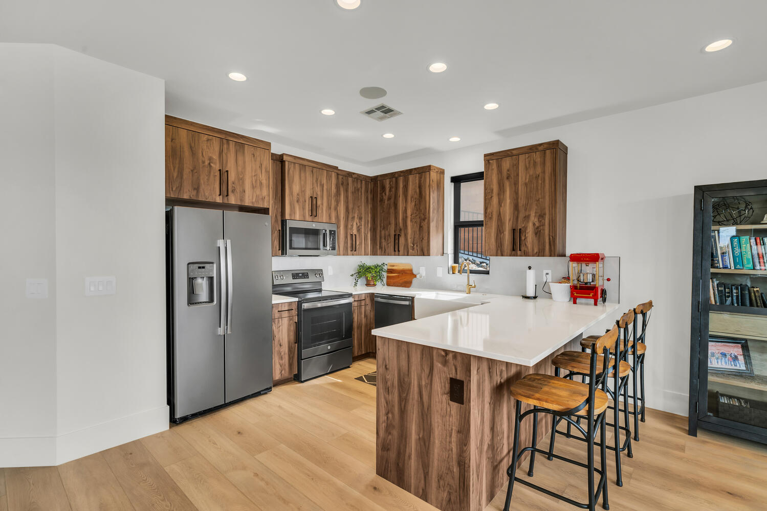 Kitchen featuring stainless steel appliances, a peninsula, a kitchen breakfast bar, light wood-style flooring, and wood finish cabinets