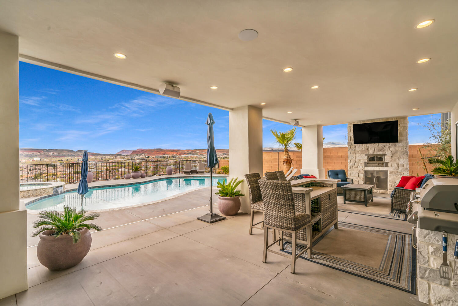 Fenced backyard with an outdoor stone fireplace, a patio, and a pool with connected hot tub