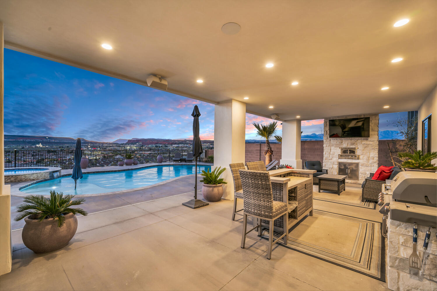 Fenced backyard featuring an outdoor stone fireplace, a patio, and a pool with connected hot tub