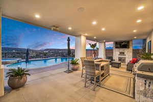 Fenced backyard featuring an outdoor stone fireplace, a patio, and a pool with connected hot tub