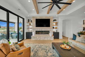 Living area with beamed ceiling, light wood-style flooring, a fireplace, ceiling fan, and recessed lighting