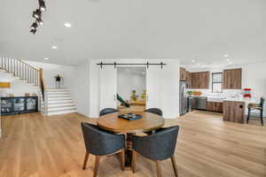 Dining area featuring a barn door, light wood-style floors, and recessed lighting