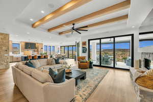 Living area featuring beamed ceiling, a fireplace, recessed lighting, light wood finished floors, and a ceiling fan