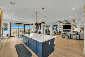 Kitchen with blue cabinets, a large fireplace, decorative light fixtures, and a center island