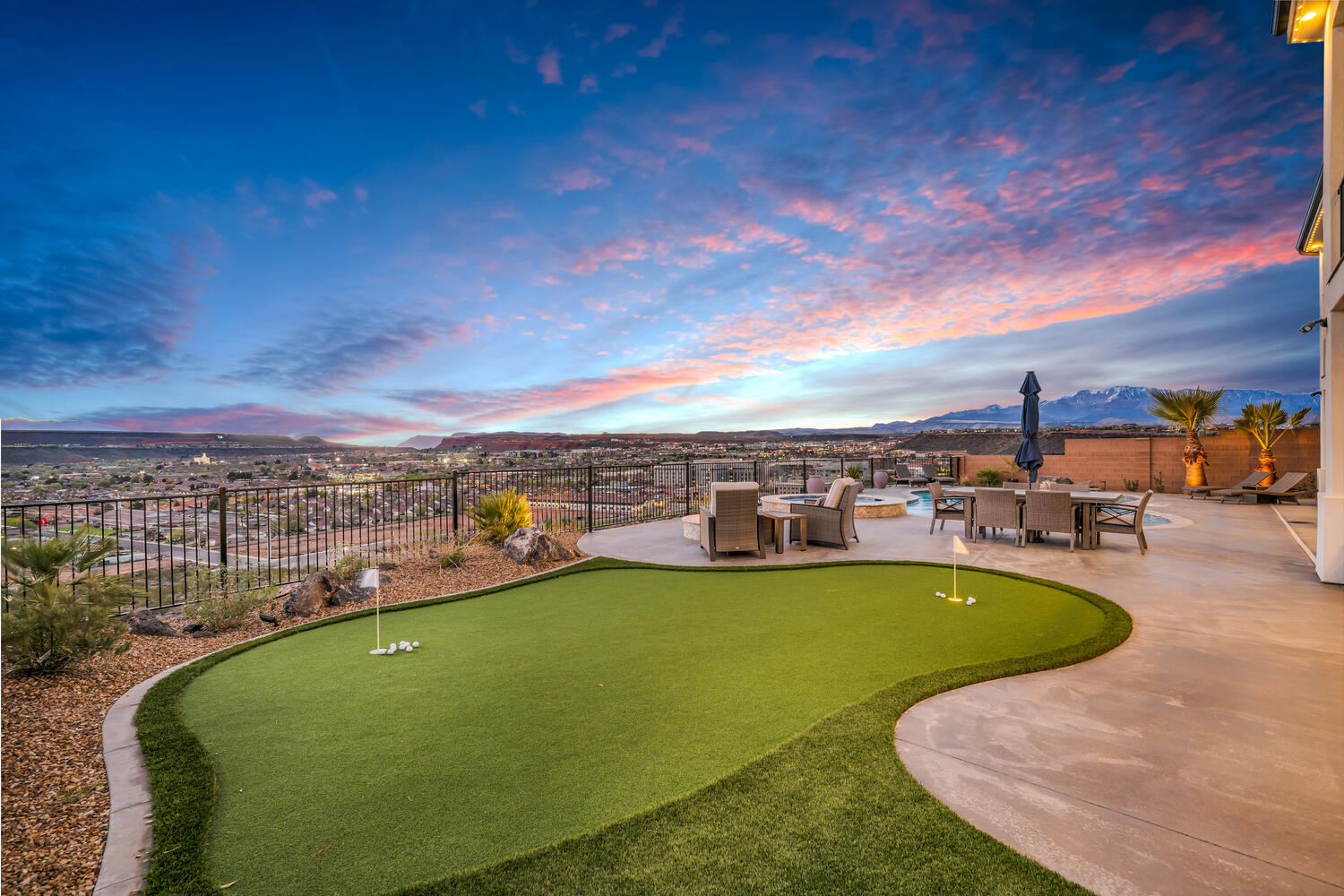 View of home's community featuring an area to practice putting, a fenced backyard, a mountain view, and outdoor dining area