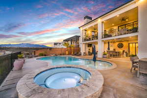 Integrated pool / hot tub with a balcony, a patio area, a fenced backyard, and outdoor dining area