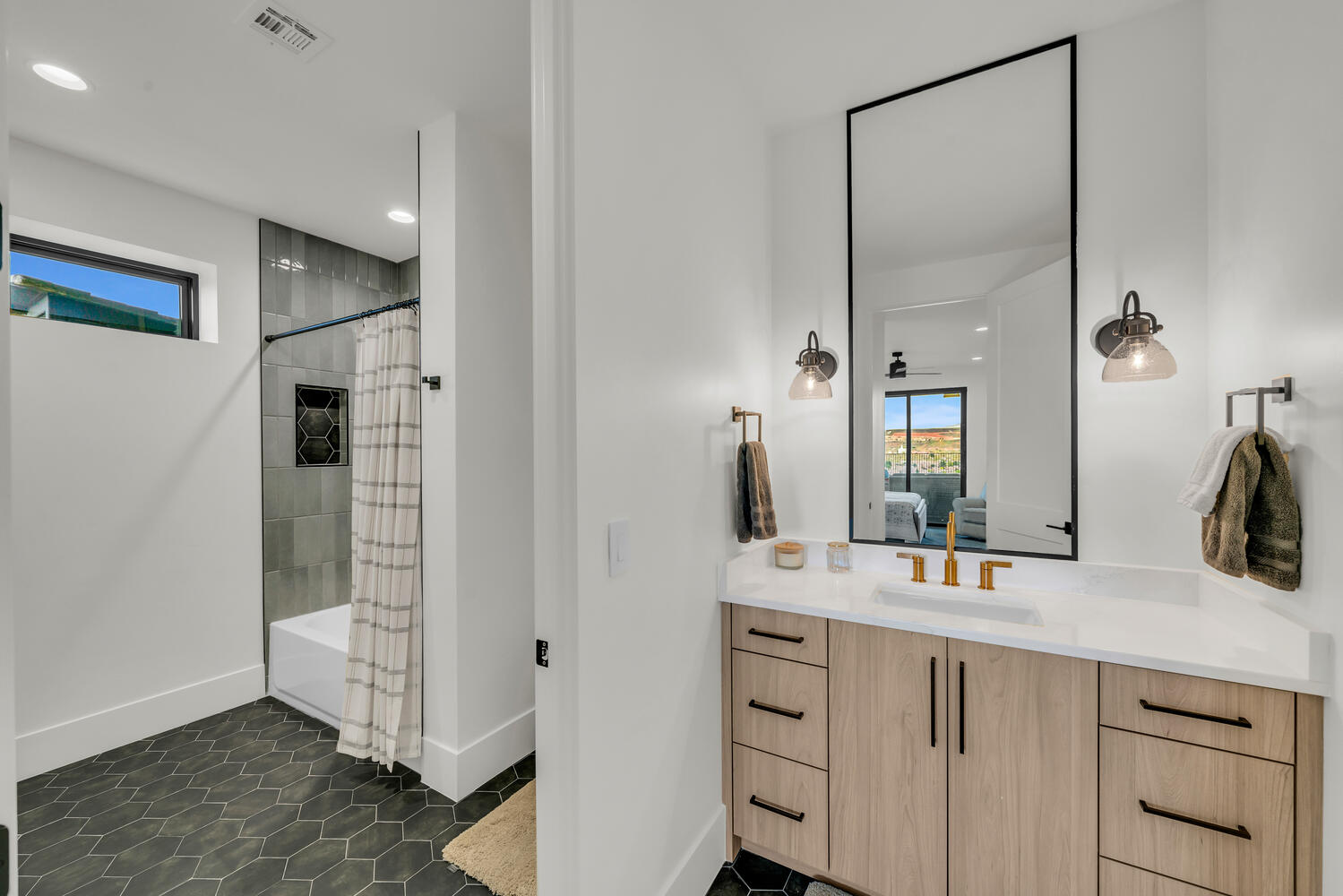 Ensuite bathroom featuring healthy amount of natural light, shower / tub combo, vanity, dark tile patterned flooring, and recessed lighting