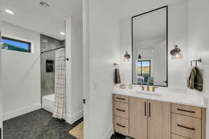 Ensuite bathroom featuring healthy amount of natural light, shower / tub combo, vanity, dark tile patterned flooring, and recessed lighting