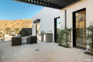 View of patio featuring an outdoor pool, kitchen and area to lounge, a pergola, and a mountain view