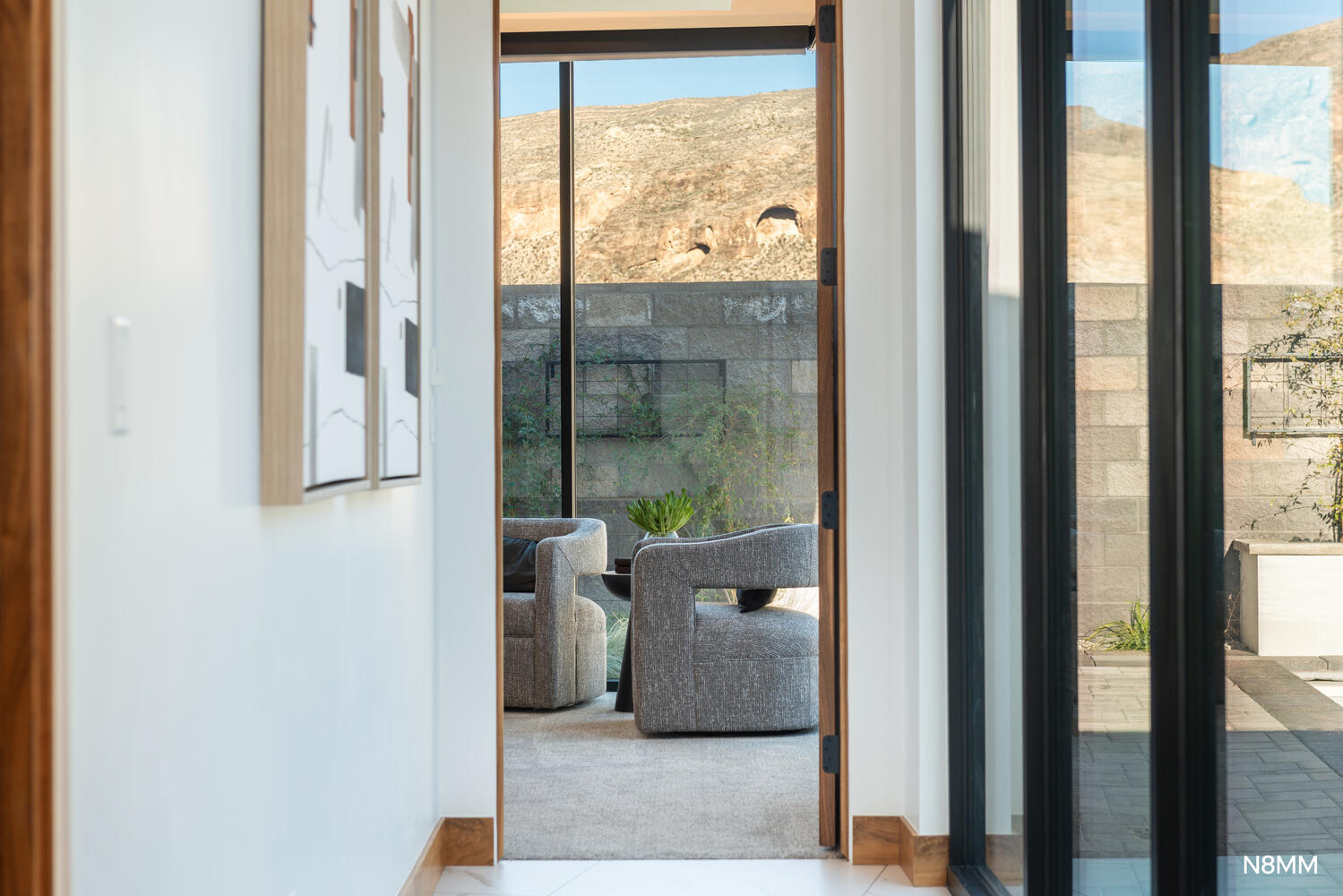 Hallway to primary bedroom featuring plenty of natural light from the sliders to the pool area.