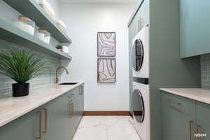 Laundry area with stacked washer / drying machine, light finish floors, ample counter and cabinet space