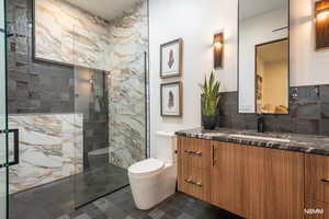 Full bathroom with a marble finish shower, vanity, and stone backsplash